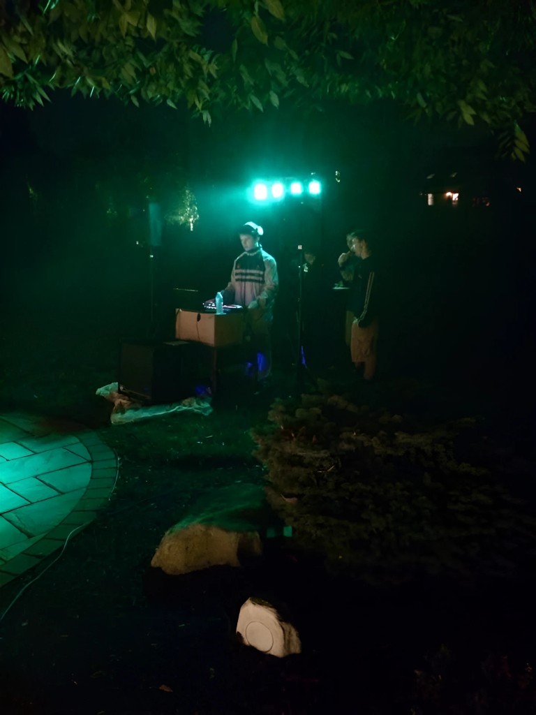 A young Jason Kushy DJing an outdoor set under green lights